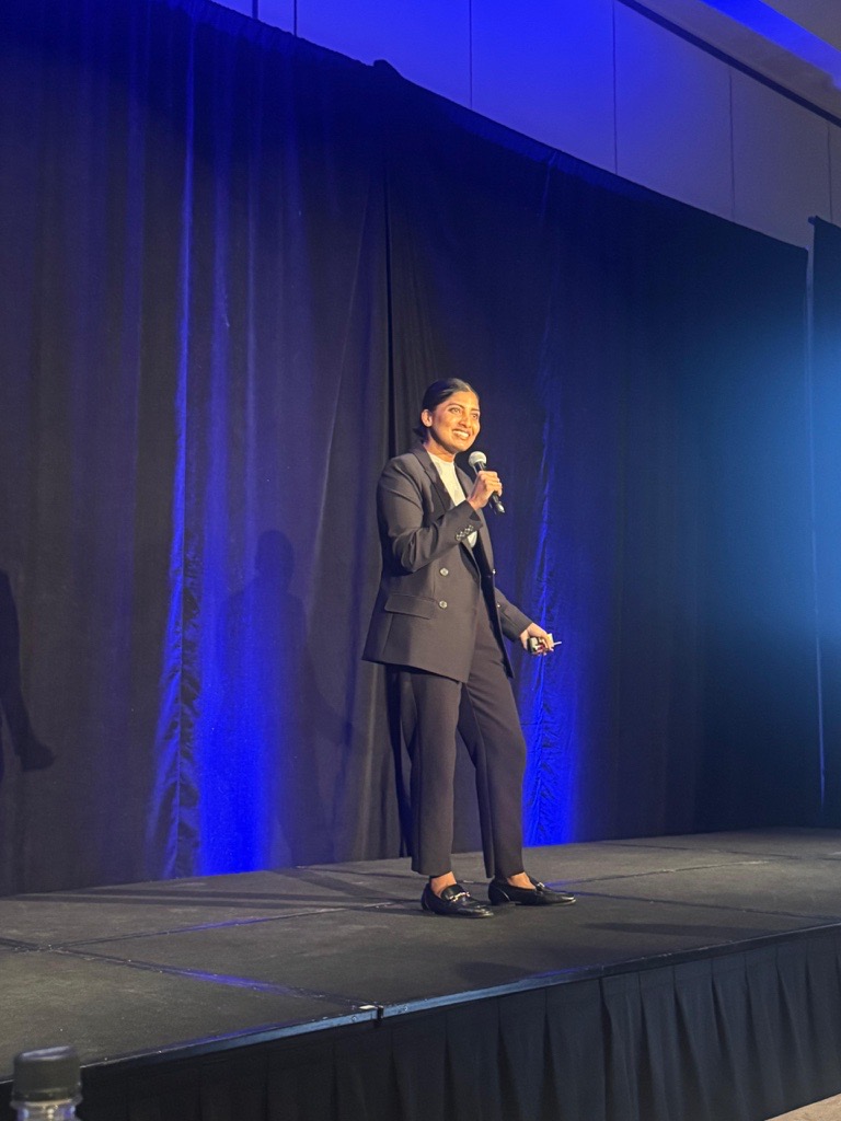 Dana Udumulla speaking on stage at a conference